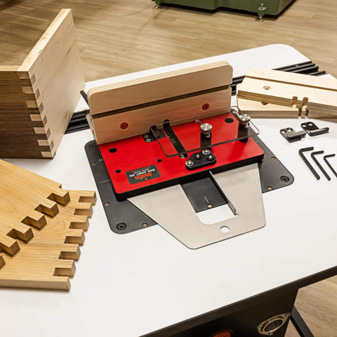 Pro Grade Box Joint Jig For Router Tables With Aluminum Indexing Keys And Smooth Bearing Glide System Includes One Quarter Inch, Three Eighths Inch, And One Half Inch Keys And Baltic Birch Fences For Precise Drawer And Box Joints set up on table with wood pieces