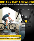 Cyclist using Magnetic Plus Indoor Bike Trainer With Wheel On Setup And Quiet Fluid Resistance For Realistic Rides No Wheel Removal Needed Linear Resistance That Matches Each Pedal Stroke And Gear Plus Easy Zwift App Connectivity For Home Gym Training in a living room