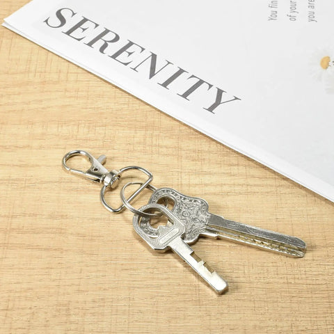 Badass Swivel Snap Hooks And D Rings Set Keychain Clips Lobster Claw Clasps attached to keys on a wooden table.