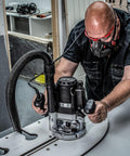 Man using Beefy Dual-Mode Plunge Router 3-1/4 HP With 1/2 Inch Collet in a woodworking shop setting
