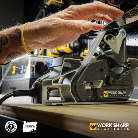 Person using Ken Onion Edition Knife And Tool Sharpening System Mk2 with adjustable angles and blade grinding attachment on workbench