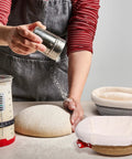 Baker using Cotton Rope Banneton Bread Proofing Basket Set With Liners And Covers, oval and round baskets on table.