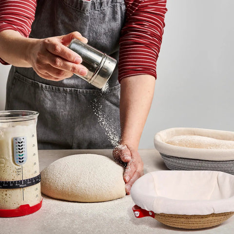 Baker using Cotton Rope Banneton Bread Proofing Basket Set With Liners And Covers, oval and round baskets on table.