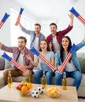 Group holding 120 Pcs Inflatable Thunder Sticks for Parties and Games Red White and Blue USA Flag Boom Sticks in living room