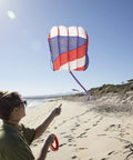 Person flying Patriot Wave 7.5 Parafoil Kite, Easy To Fly Single Line Beginner Kite With No Assembly, on a sandy beach.