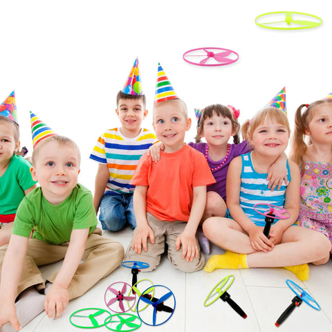Kids playing with Awesome Flying Saucer Toy Set With 32 Discs And 16 String Launchers, wearing party hats indoors.