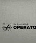 The Standard UAS Operator Logbook For Drone Pilots close-up of cover with title and logo on textured gray background.