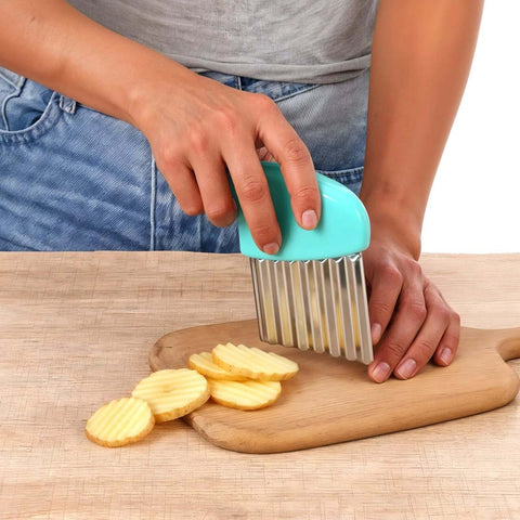Side view of XLIUAX 2-pack crinkle cutter with teal handle and stainless wavy blade slicing potato rounds on wood board