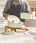 Man displaying Detachable Handle Cookware Set With Stackable Pots And Pans, Nonstick Granite Titanium, beige color, in kitchen.