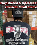Person wearing 'Bolts and Nuts' shirt and hat in warehouse, showcasing family-owned American small business setting.