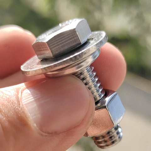 Close-up of a stainless steel hex bolt with flat washer and nut on its threaded shank