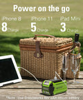 Picnic basket with electronics charging from Greenworks 40V inverter, next to wine glasses and a tablet, illustrating portable power.