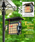 Double Suet Feeder For Outdoors Weatherproof All Metal Cage With Taller Grid Perch For Woodpeckers Easy To Clean And Refill Durable Black Bird Feeder For Outdoor Yards And Gardens, shown installed on a garden pole with two woodpeckers perched on it, highlighting its tall grid design.