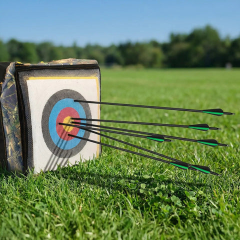 30 Inch Carbon Arrows 7 Pack With Removable Tips For Compound And Recurve Bows, 100 Grain Rotatable Broadheads, 500 Spine Practice Arrows, Hybrid Shaft For Lightweight Strength And Pinpoint Accuracy striking a target in a grassy field.