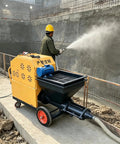 Portable Automatic Cement Mortar Plastering Spraying Machine Pump spraying cement on a construction site with operator in safety gear.