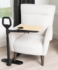 Adjustable Bamboo Tray Table With Ergonomic Safety Handle and Stand for Couch, placed beside a white armchair.