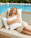 Woman relaxing with 12x20 Outdoor Pillow Inserts Pack Of 2 Waterproof Square Throw Pillows on patio sofa near pool