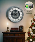 Large 15 Inch Moving Gears Wall Clock In Sleek Silver mounted on wall above a wooden cabinet, features bold numbers, vintage industrial decor.