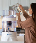 Woman using gravity water system with mineral stones replacement for mineral rich water, improves taste and alkalinity.