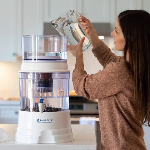 Woman using gravity water system with mineral stones replacement for mineral rich water, improves taste and alkalinity.