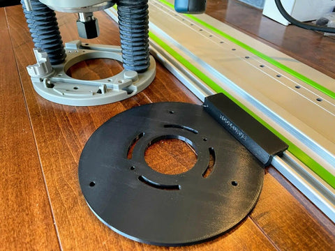 Guide Rail Adapter Fits Bosch 1617 Router Converts Plunge Or Fixed Base To Track Saw System For Dead On Cut Accuracy Uses Original Sub Base Screws For A No Sweat Install Designed And Built In America on a wooden surface next to a router.