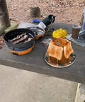 Stovetop Camping Toaster 4 Slice For Gas Stove on picnic table with toasted bread slices outdoors