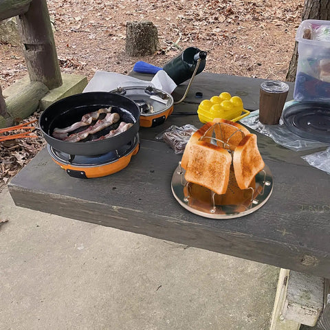 Stovetop Camping Toaster 4 Slice For Gas Stove on picnic table with toasted bread slices outdoors