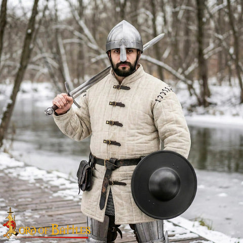 Warrior holding sword and Beefy Battle Ready 11 Inch Small Medieval Buckler Shield With Rolled Rim And Riveted Grip 16 Gauge Mild Steel For LARP Reenactment Stage Use And Display Blackened Compact Round Shield in snowy forest