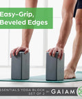 Kick Your Practice Up With This Game Changer Yoga Block Built From Lightweight EVA Foam With A Nonslip Grip And Rounded Beveled Edges That Keep You Balanced Through Pilates Vibes. Two gray EVA yoga blocks on a mat.