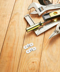 Hella Tough 100 Pack Stainless Steel U Shaped Pipe Clamps Double Hole Conduit Brackets on wooden workspace with tools.