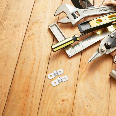 Hella Tough 100 Pack Stainless Steel U Shaped Pipe Clamps Double Hole Conduit Brackets on wooden workspace with tools.