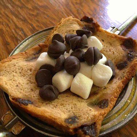 Retro 1945 Style Handheld Cast Aluminum Sandwich Maker And Pie Iron Grill with toasted bread, chocolate chips, and marshmallows.