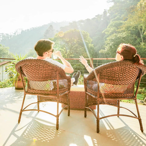 Couple relaxing in outdoor wicker chairs enjoying sunlight, showcasing Hella Durable PE Rattan Repair Cord 7Mm X 131Ft All Season Wicker Chair Replacement String.