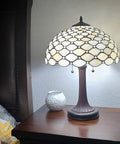 Stained Glass Banker Jeweled Table Lamp With White And Yellow Shade, 26 Inch Tall Vintage Style Nightstand Light on a bedside table.