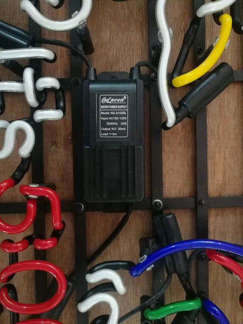 Close-up of a metal frame neon sign 17 inch by 13 inch real glass neon light, multi-colored glow, showing electrical components.