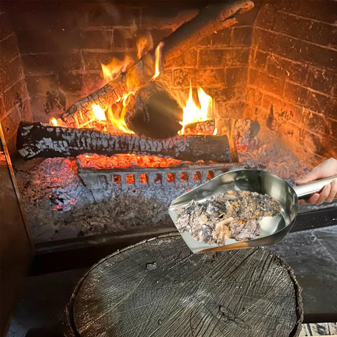 Using 14.2 Inch Fire Pit And Garden Ash Shovel to collect ash from a lit fireplace, heat resistant stainless steel design