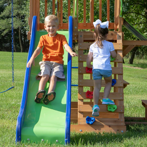 Children playing on Beachfront Cedar Wood Swing Set With Wave Slide Elevated Deck Canopy Monkey Bars Rock Wall Ladder Shaded Picnic Area