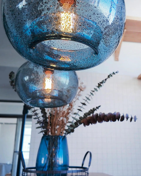 Close-up view of Stylish Hand Blown Glass Pendant Lights for Kitchen Island in Blue Marble Finish with Edison bulb off background.