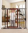 Walk Through Baby And Pet Gate With Walnut Wood And Charcoal Metal Accents installed in doorway with child standing behind