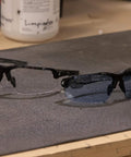 Tacana ANSI Z87.1 Safety Glasses with Anti Fog Lenses shown on a workbench, featuring polycarbonate lenses and black frames.