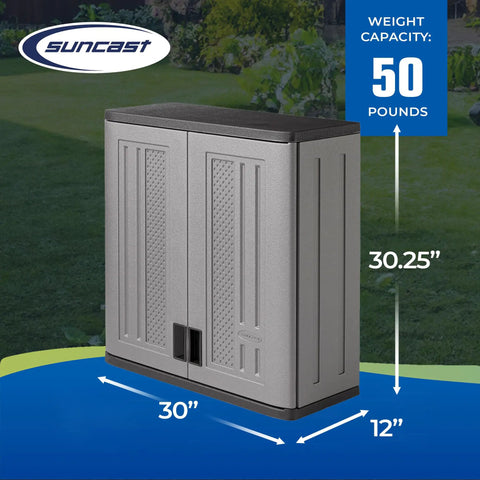 Wall Mounted Garage Storage Cabinet With Durable Resin Construction For Tough Garage Organization, 30 Inch Wide Double Wall Unit With Doors And Slate Top In Platinum Silver Finish against a green garden background.