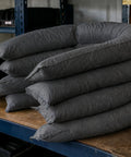 Heavy Duty Universal Absorbent Socks 12 Plus Pack Spill Containment Tubes stacked on a workbench, gray industrial-grade design.