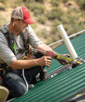 Worker applying All Weather Clear Roof Sealant 10.5 Oz Cartridge Pack Of Twelve Waterproof Leak Stopper on metal roof.