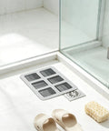 80Pcs 4x4 Disposable Hair Drain Stickers Anti Blocking on bathroom floor near shower, capturing hair and debris.