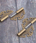 Two Piece Brass Flower Cloud Hinge Set For Jewelry Boxes And Furniture Decor With Screws 60 By 55mm on wooden surface