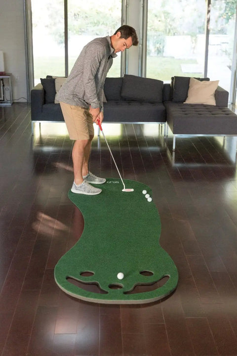 Man using Indoor Putting Green For Home Golf Practice With Realistic True Roll, Three Cups And Workable Bunkers, 3x9 Feet
