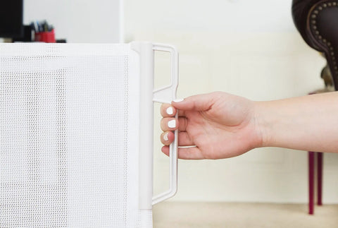 Close-up of hand holding Retractable Indoor Outdoor Pet Safety Gate For Doorways And Stairs Up To 54 Inches Ultra Space Saving Super Easy To Move.