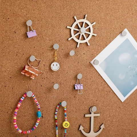 Badass 100 Piece Heavy Duty Flat Head Thumb Tacks With A Sharp Silver Finish And A Nifty Storage Canister used to secure notes and decor on corkboard.