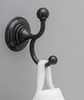 Providence Double Towel Hook In Venetian Bronze With SpotShield Technology mounted on wall holding a towel.