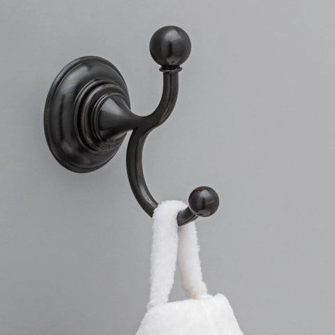 Providence Double Towel Hook In Venetian Bronze With SpotShield Technology mounted on wall holding a towel.